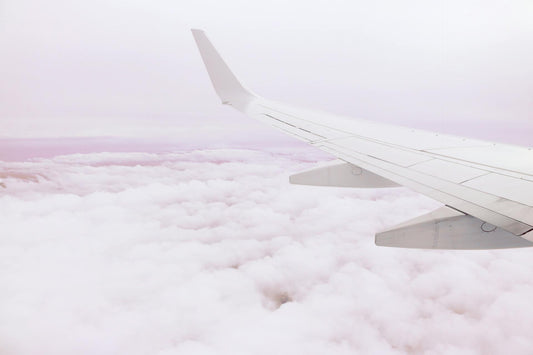 Photograph of airplane wing above clouds